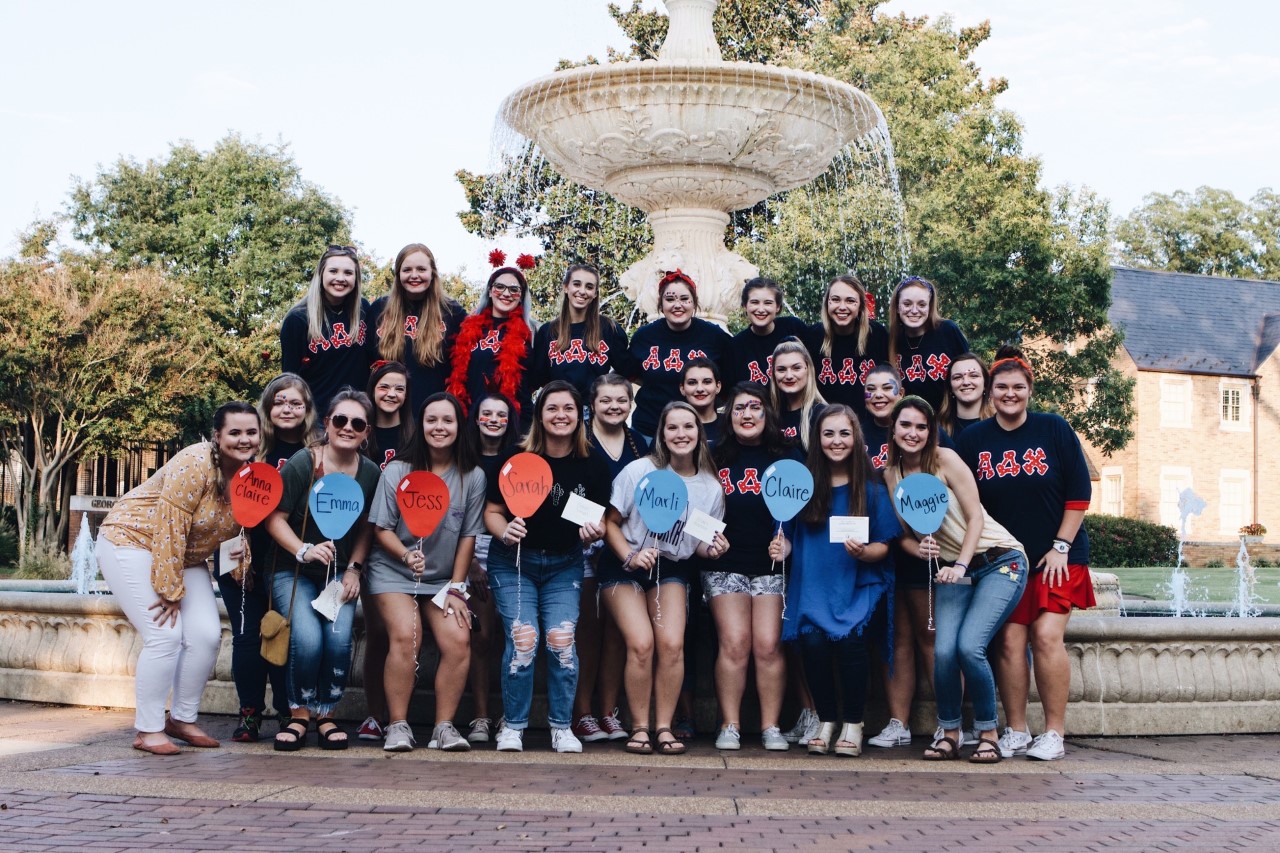 Members of Alpha Delta Chi pose for a group photo in front of the fountain